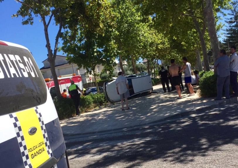 Un coche vuelca en plena avenida del Mar en Gandia y cae sobre el paseo